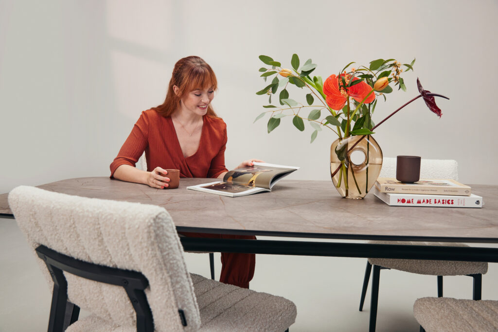 Vrouw zit aan eettafel met bloemenvaas